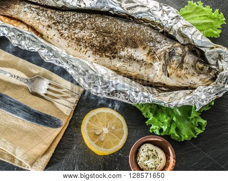 Grilled sea bass fish on the gray table.