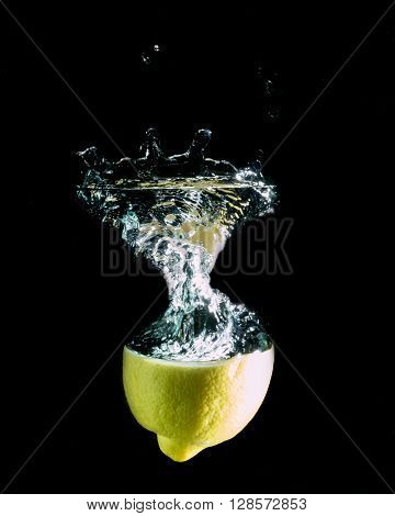 lemon on a black background, falling on the water