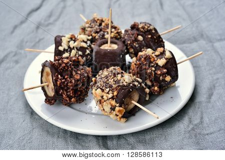 Frozen banana covered with chocolate and peanuts
