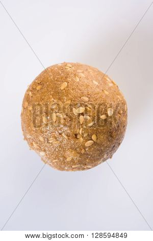 tilgul laddu or til gul laddu spread over white background, selective focus, single laddu isolated, showing texture
