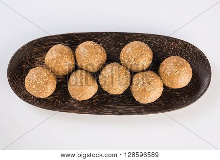 wooden plate full of tilgul laddu or til gul laddu over white background, selective focus