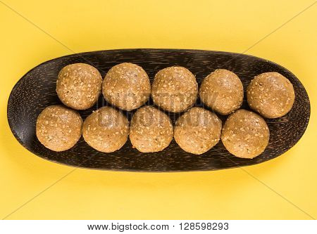 wooden plate full of tilgul laddu or til gul laddu over white background, selective focus