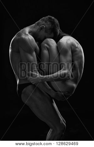Nude sexy couple. Art photo of young adult man and woman. High contrast black and white muscular naked body on black background