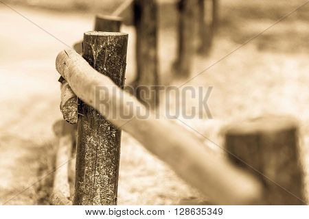 fragment of an old column and poles from a wooden fence for the ranch closeup on an indistinct background of color sepia