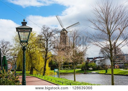 Leiden, Netherlands - April 7, 2016: Windmill de Valk in Leiden, street light and canal, Holland, Netherlands in spring