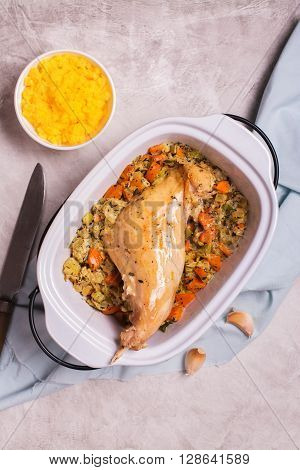 Roasted rabbit legs, vegetables stew and polenta over stone table. Top view