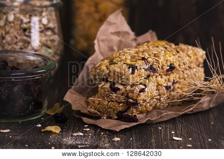 Stack of cereal bars with oat, cranberry, nuts and corn flakes over wooden table