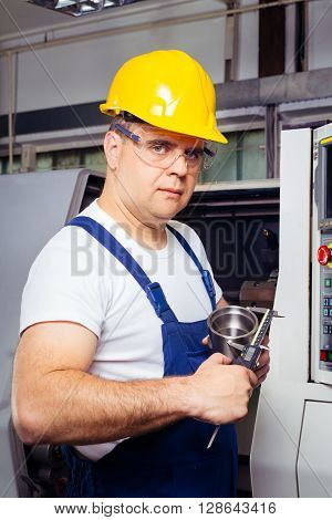 Factory man worker measuring steel detail with digital Vernier Caliper at workshop