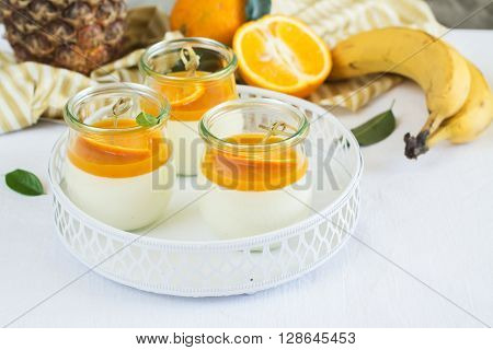 Vanilla panna cotta with exotic fruits sauce over dark wooden table. Selective focus