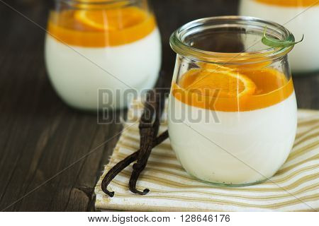 Vanilla panna cotta with exotic fruits sauce over dark wooden table. Selective focus
