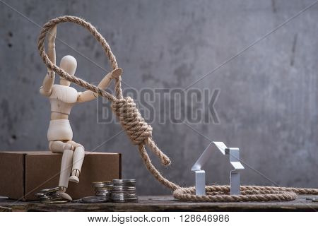 Small Wooden Dummy Sitting With Hangman's Noose, House And Coins