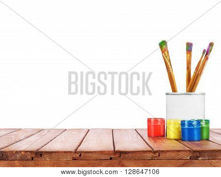 set of different brushes pencils palette knife in the bank next to the oil paints on a wooden table on a white background