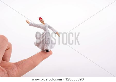 Hand holding a Sufi Derviş on a white background
