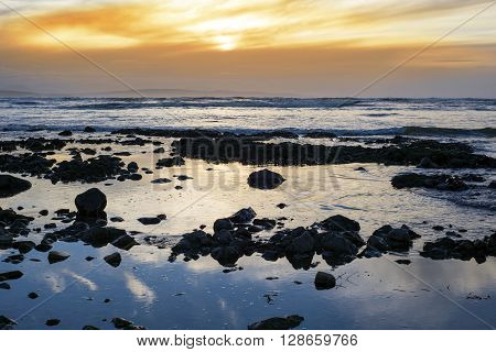 reflections at rocky beach near ballybunion on the wild atlantic way ireland with a beautiful yellow sunset