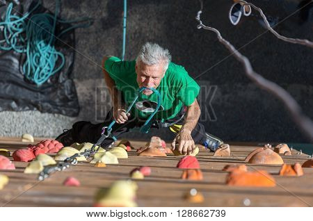 Aged Male Climber Moving Up on Outdoor Climbing Wall on Veterans Extreme Sport Competitions