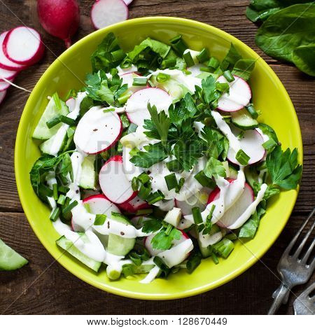 Green salad with radish spinach cucumber and greens with yogurt sauce. Useful and healthy food.