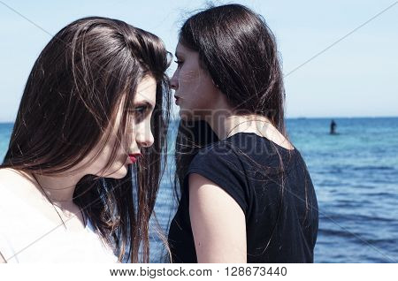 Sisters At Beach Hugging Each Other. Portrait Of Beautiful Young