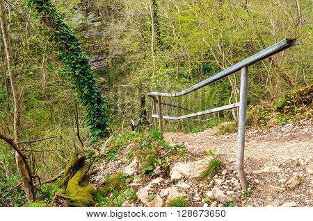Roadside of mountain forest trail with fence and gravel