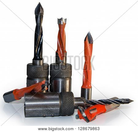 Machine tool cutters and drill bits in the sawdust on wood background