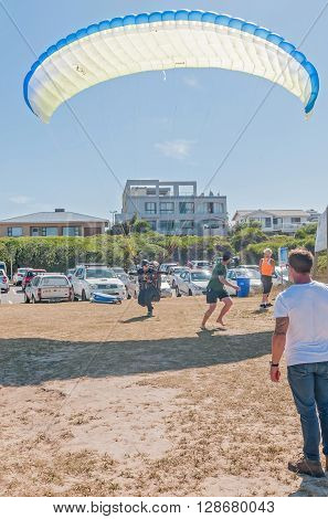 KNYSNA SOUTH AFRICA - MARCH 3 2016: A paraglider landing between people at a beach in Buffelsbaai (Buffalo Bay) a small town in the Knysna municipal area
