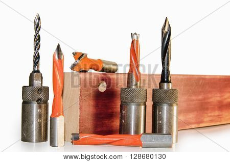 Machine tool cutters and drill bits in the sawdust on wood background