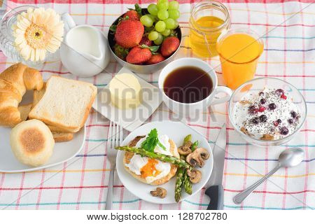Breakfast with tea, orange Juice, poached egg, salmon, asparagus, berries, Porridge seeing from the top view