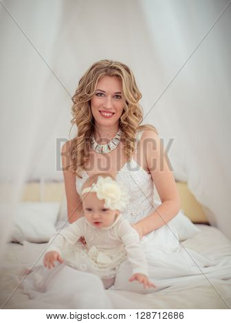 Beautiful woman with baby girl in white dress