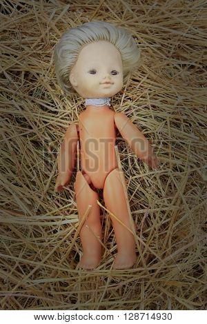 old abandoned doll lays on the hay