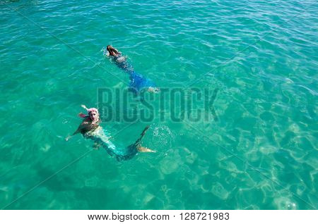 COOGEE,WA,AUSTRALIA-APRIL 3,2016: Two live interactive mermaid entertainers swimming in the turquoise Indian Ocean waters at the Coogee Beach Festival in Coogee, Western Australia.