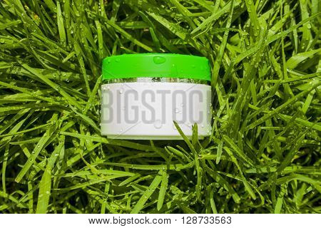 Cosmetic cream on a background of green grass. Natural cosmetic.