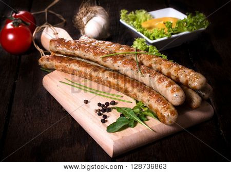Image of grilled sausages on wooden board selective focus