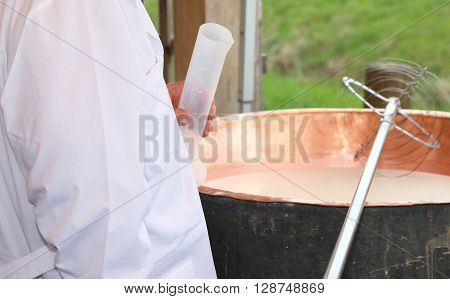 Dairyman With Plastic Tube To Pour The Rennet Into The Milk