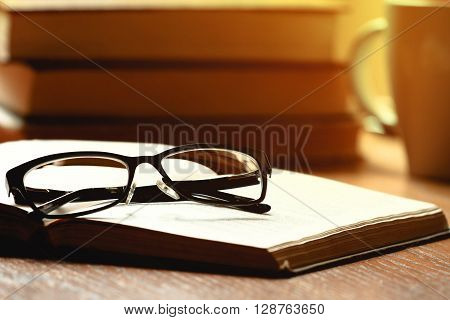 Glasses, book and cup of tea on a wooden table