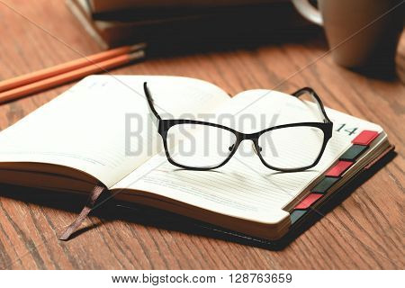 Glasses, book and cup of tea on a wooden table