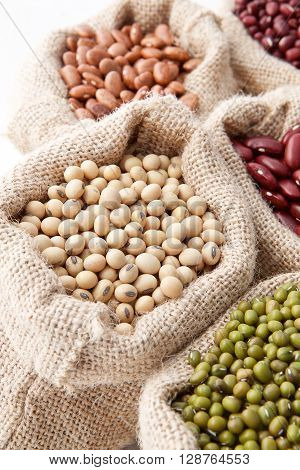 Assortment Of Beans And Lentils In Hemp Sack On Wooden Background. Green Bean, Groundnut, Soybean, R