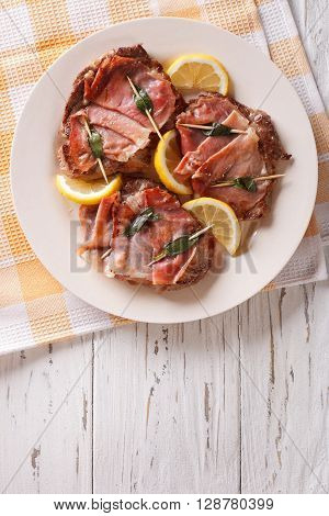 Italian Cuisine: Beef Saltimbocca With Lemon Close Up. Vertical Top View