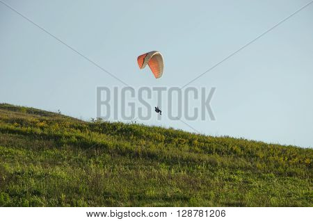 Silhouette of paraglide flying in the sky with clouds in a light of sunrise. Ukrainian Carpathian valley.