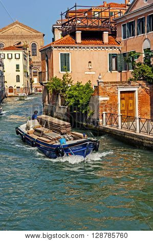 Venice, Italy - September 7, 2012: Boat loaded with construction materials makes its way on Venice canal