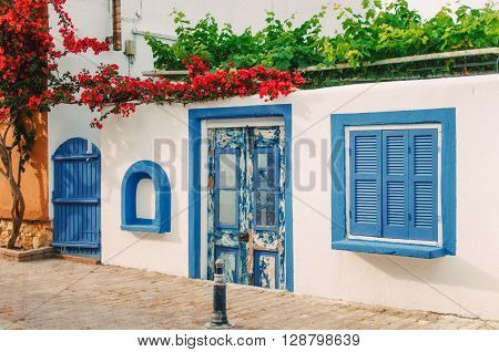 Facade of a very small white house with blue windows in Halkidiki Greece