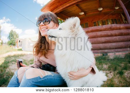 young stylish hipster woman girl playing white kid-skin dog in country side.