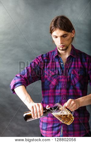 Alcohol liquor drinking relax party concept. Tapster fills stein from bottle. Young male bartender empties beer into glass.