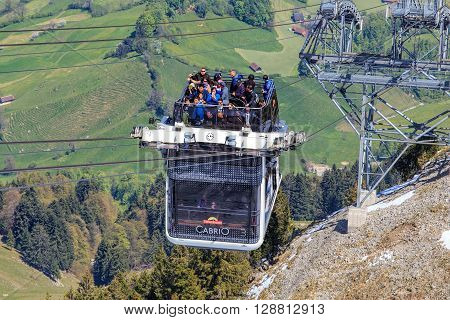Mt. Stansenhorn, Switzerland - 7 May, 2016: people in a gondola of the Stansenhorn Cabrio cable car approaching the station on the top of the mountain. Stansenhorn Cabrio is the the world's first double deck open top cable car.