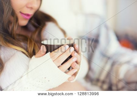 portrait of beautiful young woman with cup of coffee. brown-haired woman in a white sweater holding a cup of tea