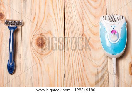 electric epilator with a razor on a light wooden background.
