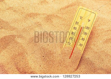 Thermometer with celsius and farenheit scale on extremely warm beach sand showing record high temperatures