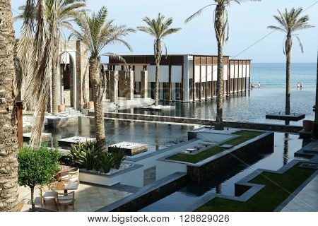 HERAKLION, CRETE, GREECE - MAY 13, 2014: The big blue swimming-pool modern building with columns palms and beach in luxury class hotel on the MeGrecotel Amirandes diterranean coast of Crete, May 13, 2014, Greece.