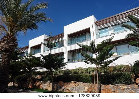 HERAKLION, CRETE, GREECE - MAY 13, 2014: The blue sky modern building of villa with balcones and palms on the terrain of luxury class hotel Grecotel Amirandes on the Mediterranean coast of Crete, May 13, 2014, Greece.