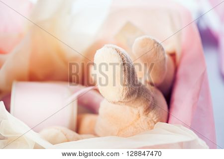 Lovely baby girl hamper gift with teddy bear soft toy and cup in delicate pink and ivory tissue paper. Gift idea for baby girl newborn.