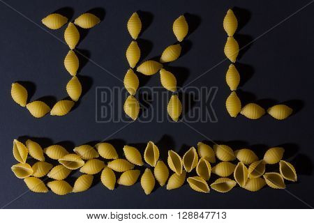 English alphabet laid out in the form of pasta shells , shot against a dark background.