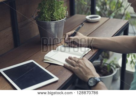 Man Writing On Notebook With Digital Tablet